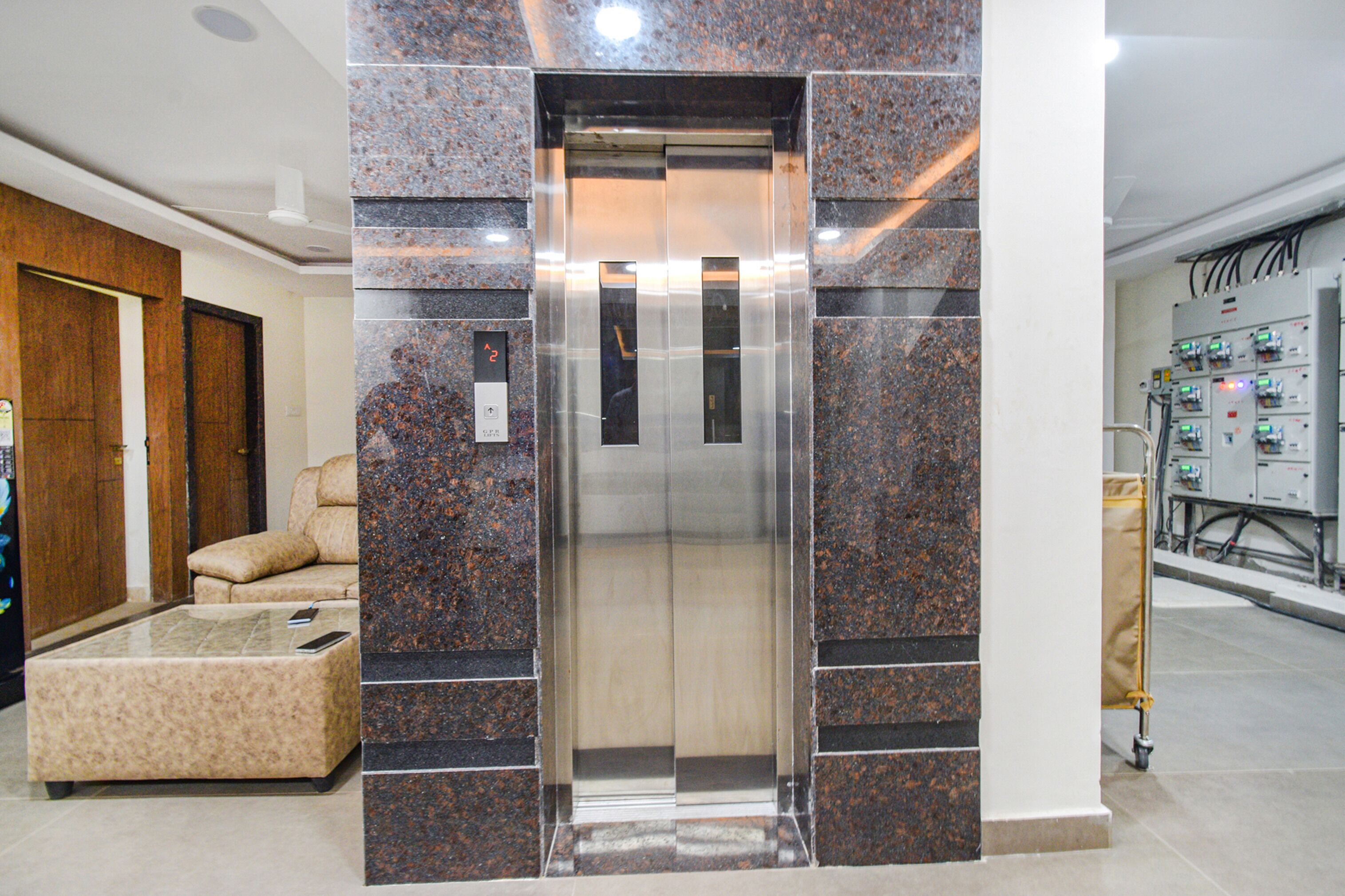 Um elevador com design moderno, ladeado por paredes de granito, um sofá confortável e uma mesa de centro de vidro.