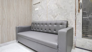 Ein modernes Wohnzimmer mit grauem Sofa, einer Wand aus Holzlamellen und einer Marmorwand mit der Aufschrift 'PULL'.
