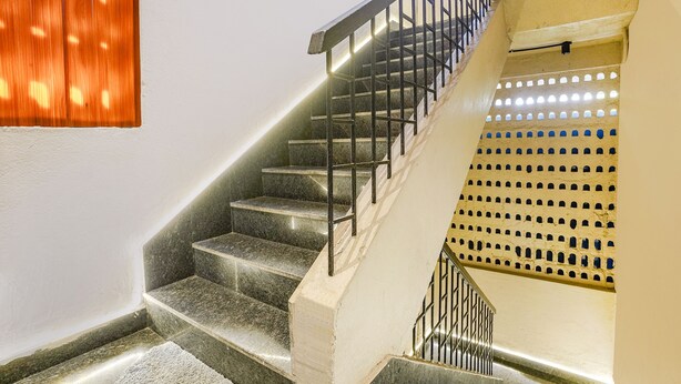 Eine Treppe mit Metallgeländer und Wandgestaltung mit Löchern.