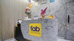 Ein Empfangstresen mit Marmorplatte, ein Schild mit der Aufschrift 'fab hotels' und eine dekorative goldene Statue.