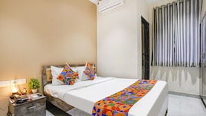 Ein Hotelzimmer mit Bett, Nachttisch, Lampe und Klimaanlage.