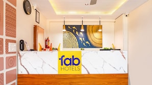 Un comptoir d’accueil d’hôtel avec un dessus en marbre, une partie inférieure en bois et une enseigne indiquant « fab hotels ».