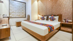 Una habitación de hotel moderna con una cama grande, un escritorio, una silla y un ventanal con persianas.
