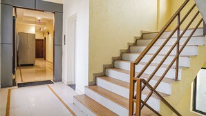 A staircase with wooden handrails, a tiled floor, and a door leading to another room. - Fabhotel Phoenix Inn (Pune)