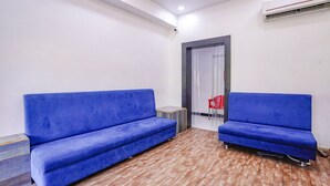 Une pièce avec deux canapés bleus, une petite table d’appoint en bois et un fauteuil rouge.