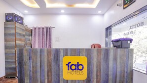 Un comptoir d’accueil avec un panneau décoratif en bois et une enseigne indiquant « fab hotels ».