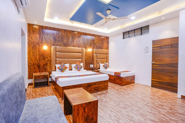 Una habitación de hotel moderna con una cama grande, dos mesitas de noche, un ventilador de techo y una pared decorativa de madera.