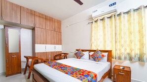 A bedroom with a bed, wooden wardrobe, bedside table, and a nightstand. - Fabhotel Crosscut (Coimbatore)