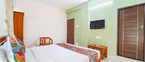 Un dormitorio con una cama, una mesita de noche de madera, un escritorio, un televisor y un armario.