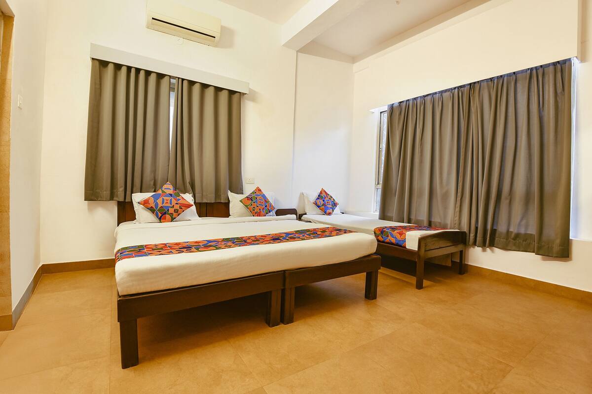 A hotel room with two beds, a large window, and a ceiling fan.