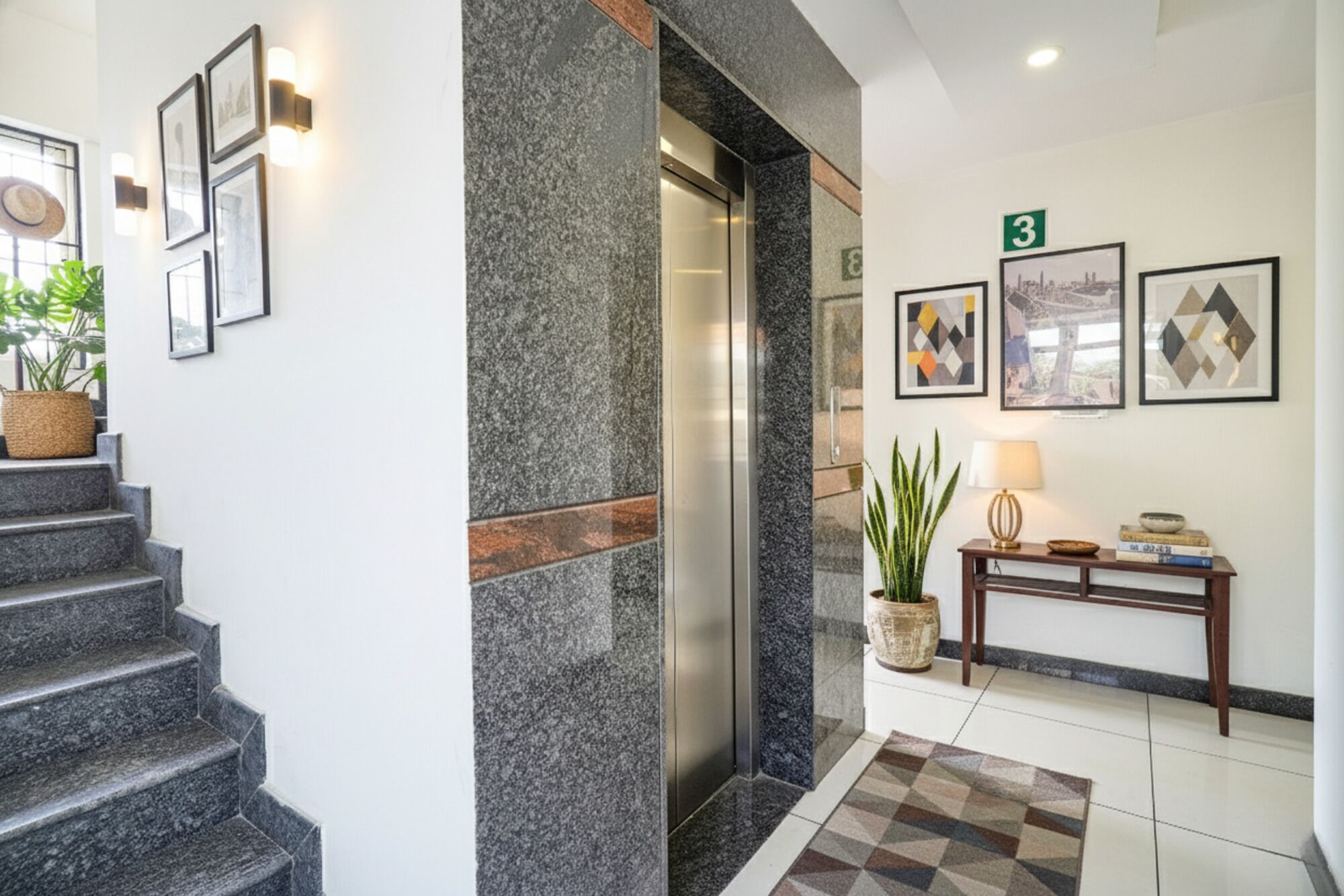 Un'elegante hall d'hotel con una scalinata in marmo, una reception e opere d'arte incorniciate alle pareti.