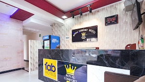 Zona d'admissió d'hotel amb un taulell de marbre, un refrigerador de Pepsi i un cartell del Royal Comfort Hotel.