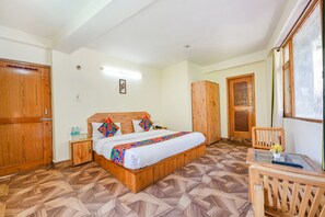 A bedroom with a wooden bed, a nightstand, a chair, and a small table with a vase. - Fabhotel Hadimba Valley (Manali)