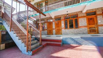 A multi-level hotel with a wooden staircase, multiple wooden doors, and a balcony.