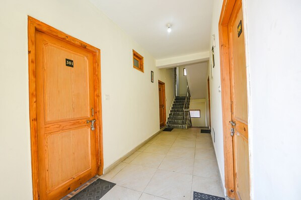 Un pasillo con puertas de madera, una escalera y suelo de baldosas.