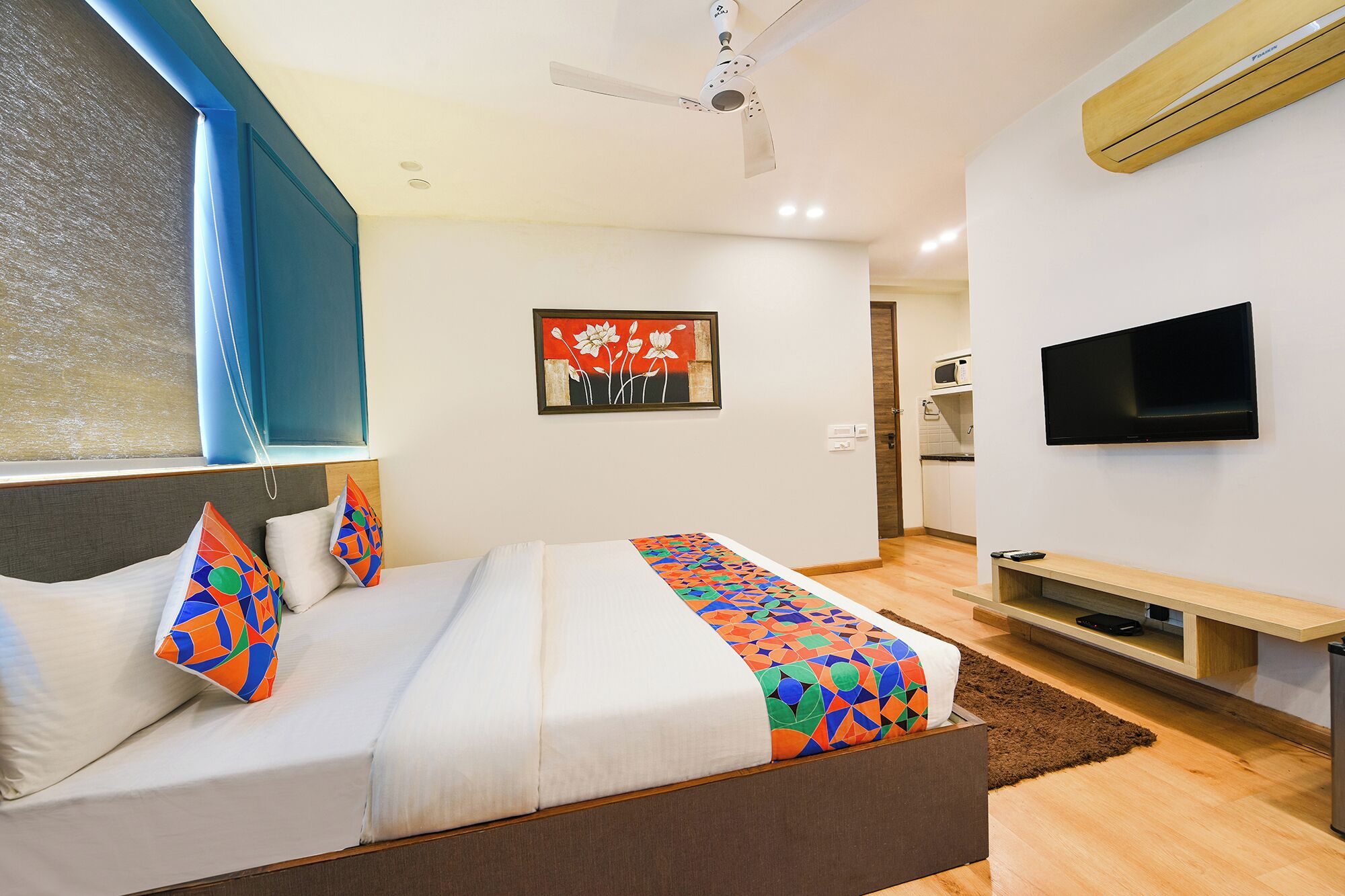 A modern hotel room with a bed, a TV, and a ceiling fan.