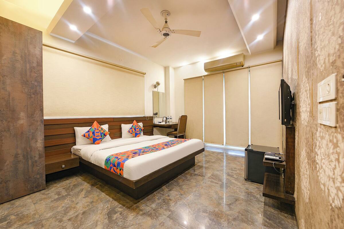 A hotel room with a bed, a desk, a chair, a television, and a wardrobe.