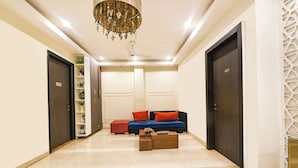 A hallway with a sofa, a coffee table, and a chandelier. - Fabhotel Micasa (Gurugram)