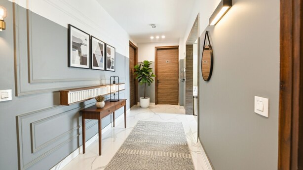 A hallway with a wooden bench, a potted plant, a mirror, and framed artwork on the wall. - Fabhotel Micasa (Gurugram)