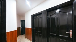 Un couloir avec des portes noires, des lambris en bois et un sol carrelé.