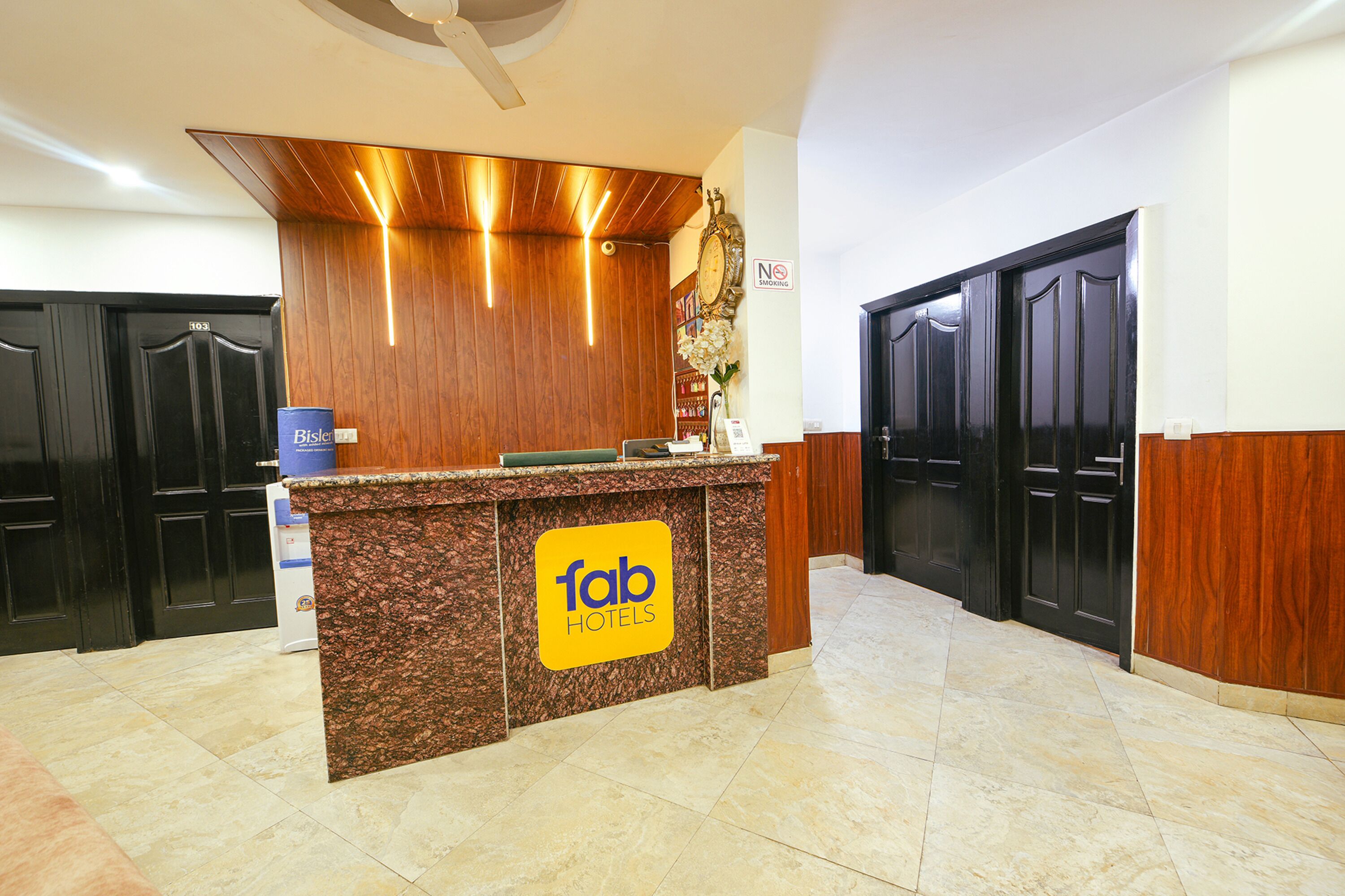 A hotel reception desk with a 'fab hotels' sign, a 'no smoking' sign, and a clock on the wall.