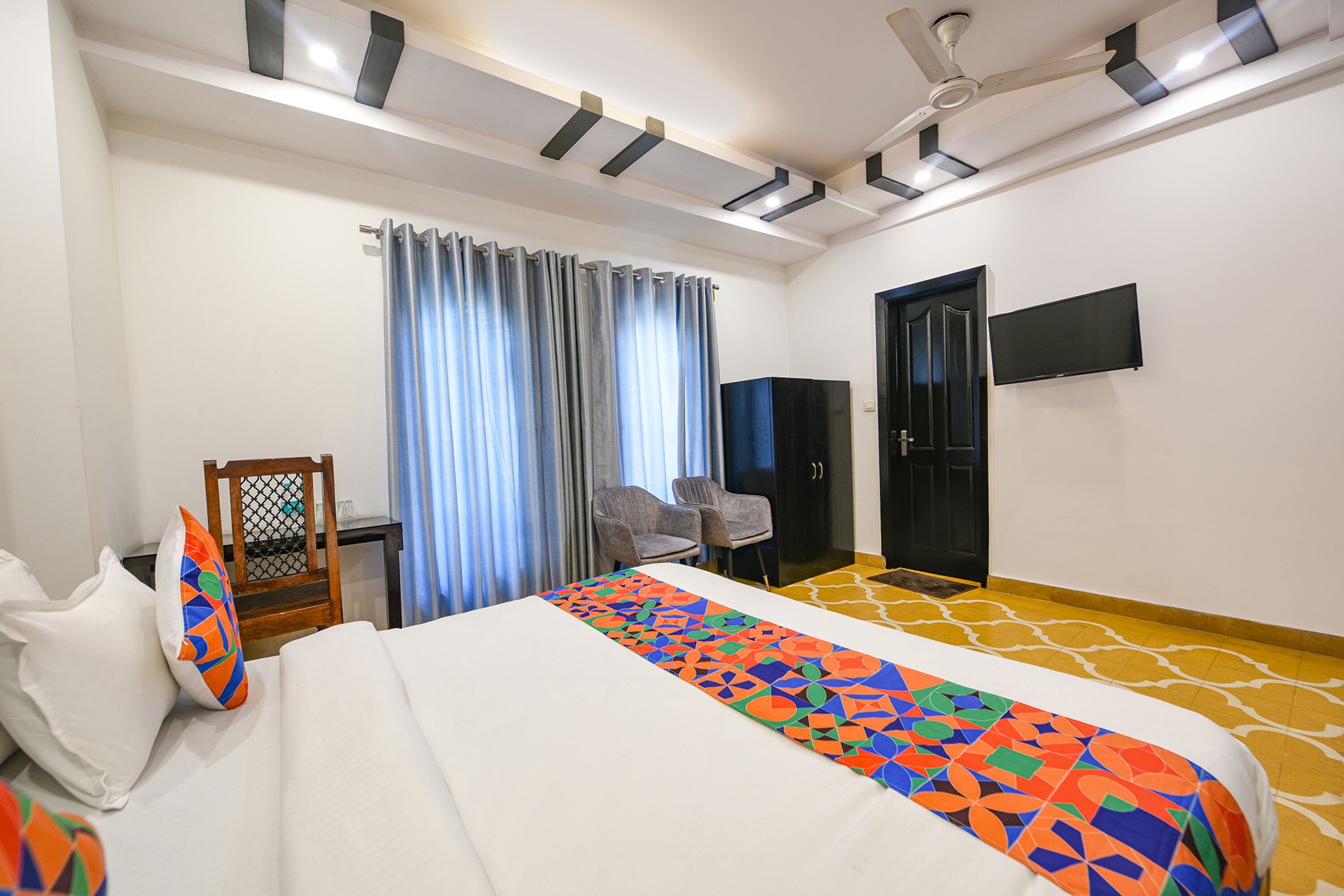 Una habitación de hotel con cama, escritorio, silla, televisor y puerta.