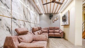 A modern living room with a sectional sofa, marble walls, and a ceiling fan.