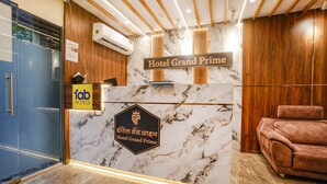 A reception desk with a sign reading "Hotel Grand Prime" and a logo.