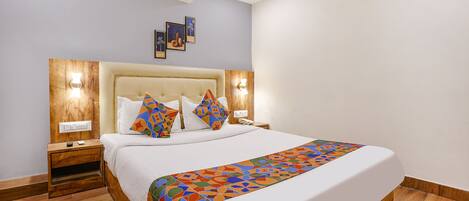 A neatly made bed with a colorful geometric-patterned bedspread, wooden headboard, and two bedside lamps.