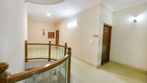 A hallway with a wooden staircase, a door, and a light fixture on the wall. - Fabhotel Alpine Tree (Amritsar)