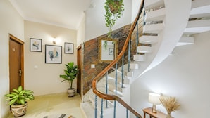 A staircase with a wooden handrail and blue balusters, leading to a landing with a white wall and framed artwork. - Fabhotel Alpine Tree (Amritsar)