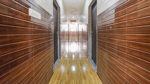 A hallway with wooden paneling and a polished floor, leading to a bright, well-lit area. - Fabhotel Maa Gayatri Sadan (Mathura)