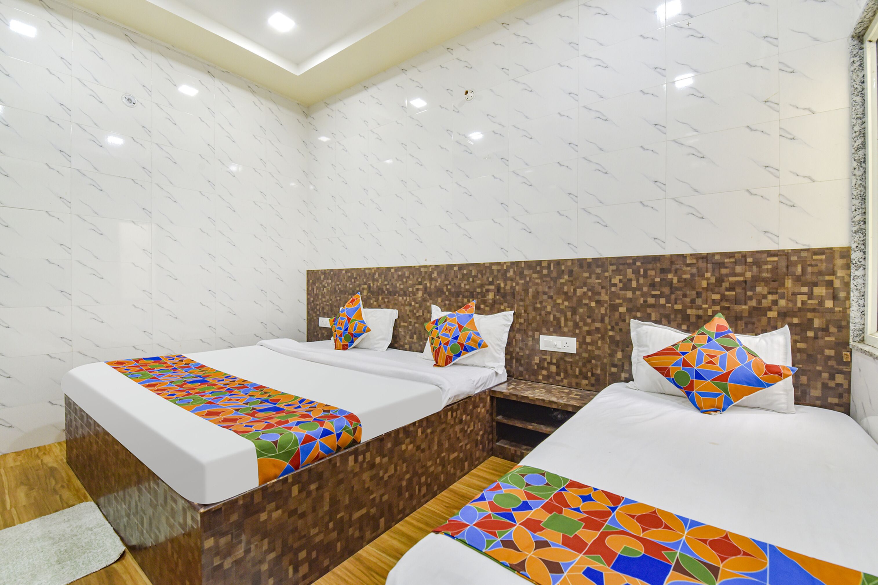 Habitación de hotel con dos camas, una mesita de noche y una pared de azulejos.