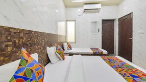 A hotel room with two beds, a wooden headboard, a tiled wall, an air conditioning unit, and a door. - Fabhotel Maa Gayatri Sadan (Mathura)