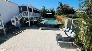 Ein Garten mit Swimmingpool, überdachter Terrasse und Gartenmöbeln.
