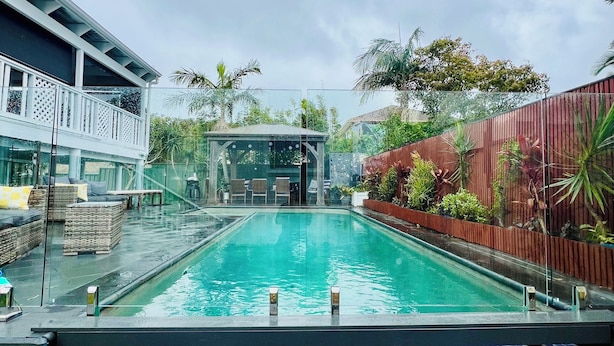 Ein Schwimmbecken mit Mosaikfliesen, umgeben von Gartenmöbeln und Pflanzen.