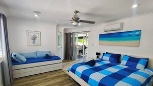 Ein Schlafzimmer mit einem Bett, einem Schlafsofa, einem Deckenventilator und einem Bild an der Wand.