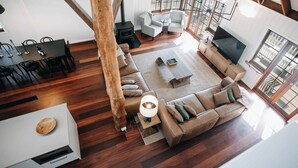 Amplia sala de estar con un sofá grande, un televisor y una chimenea. Cuenta con una mesa de comedor con sillas y piso de madera.