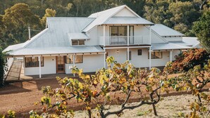 Una casa de dos pisos con balcón, rodeada de un viñedo.