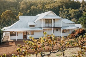 A two-story house with a balcony, surrounded by a vineyard.