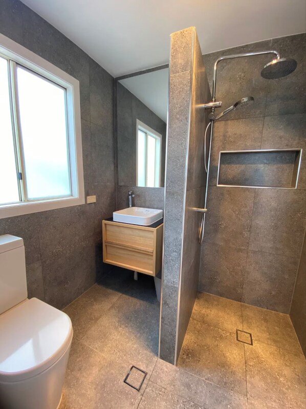 Une salle de bain moderne équipée d’une douche, de toilettes et d’un meuble-lavabo.