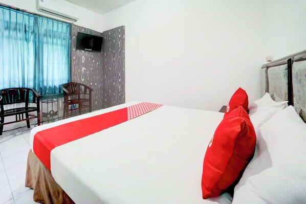 A hotel room with a bed, a TV mounted on the wall, a window with curtains, and a seating area with chairs. - Hotel O Bungurasih Near Juanda International Airport Formerly Griya Waru Hotel (Surabaya)