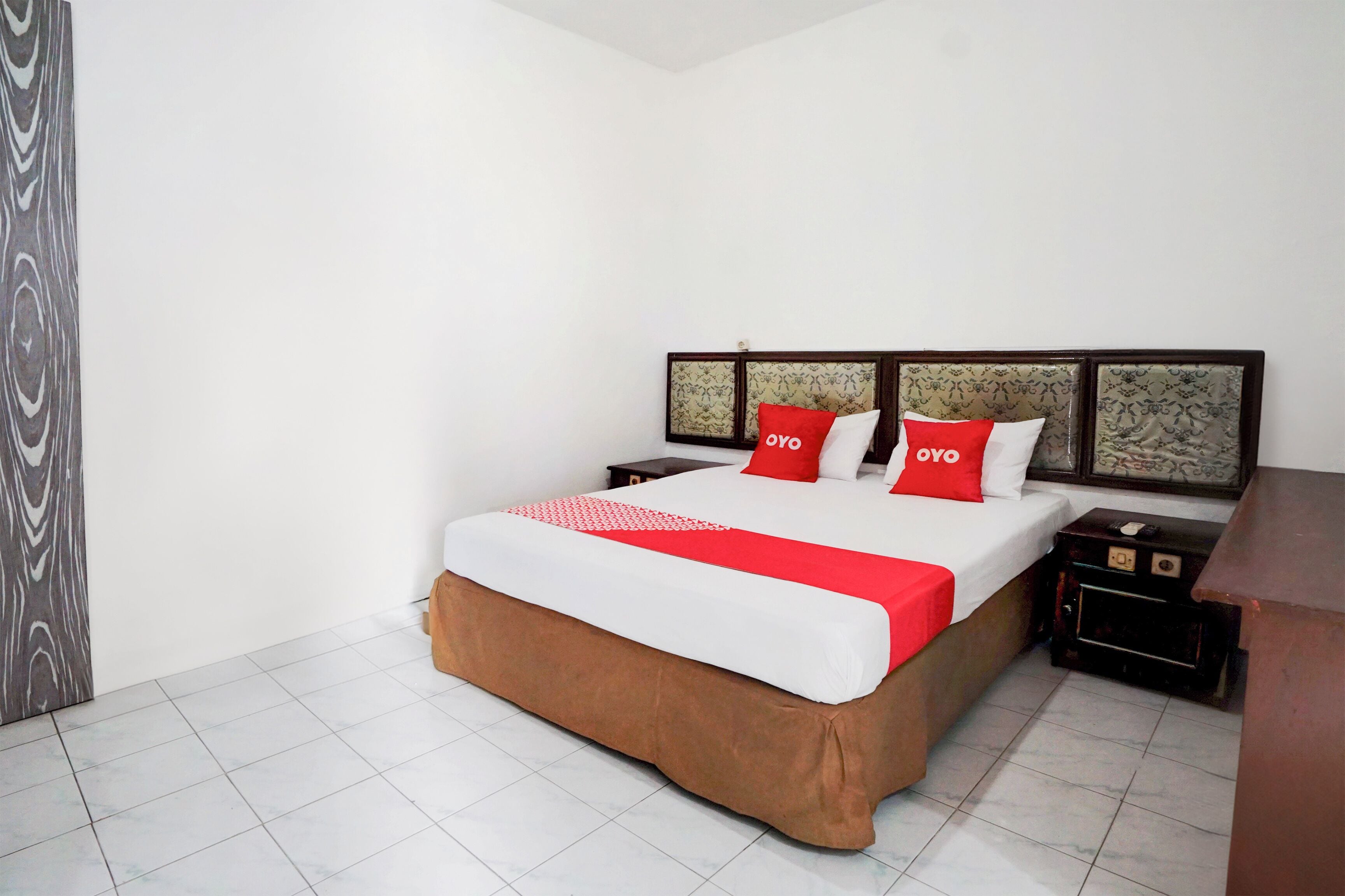 A neatly arranged hotel room with a large bed, a nightstand, and a wooden headboard.