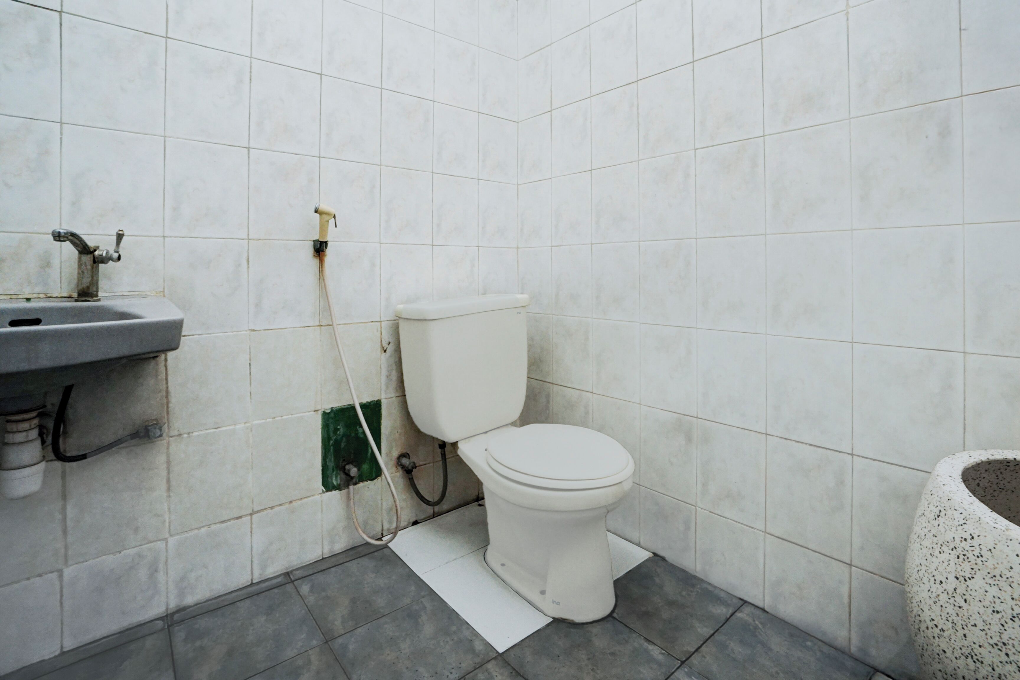 Et lille badeværelse med toilet, håndvask og brusebad.