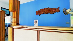 Una recepción con diseño de madera, pared azul y un cartel que dice "HOTEL GRIYA NOUMI".