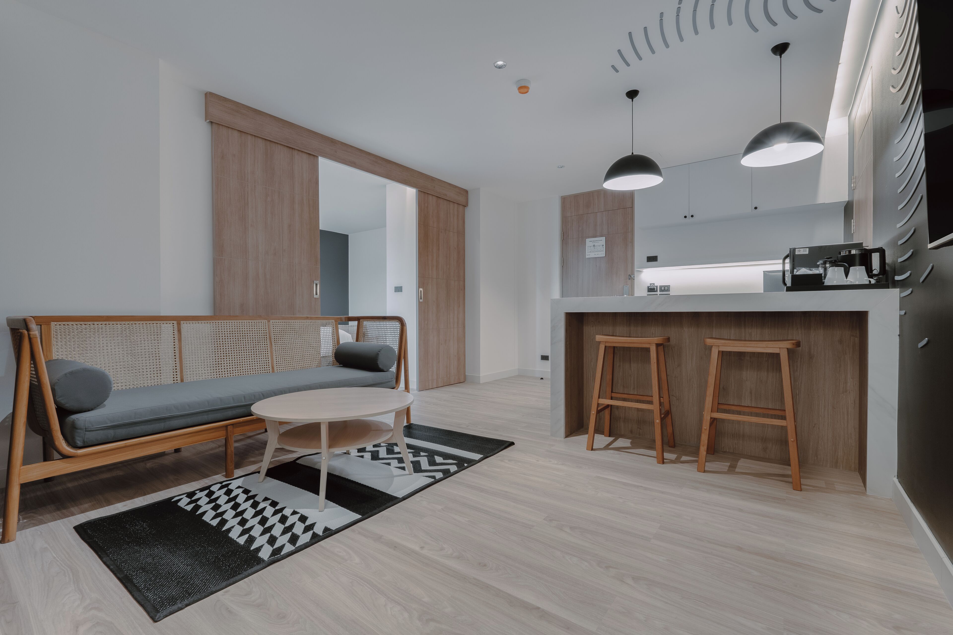 Une cuisine moderne avec des armoires en bois, un bar intégré et des luminaires suspendus.