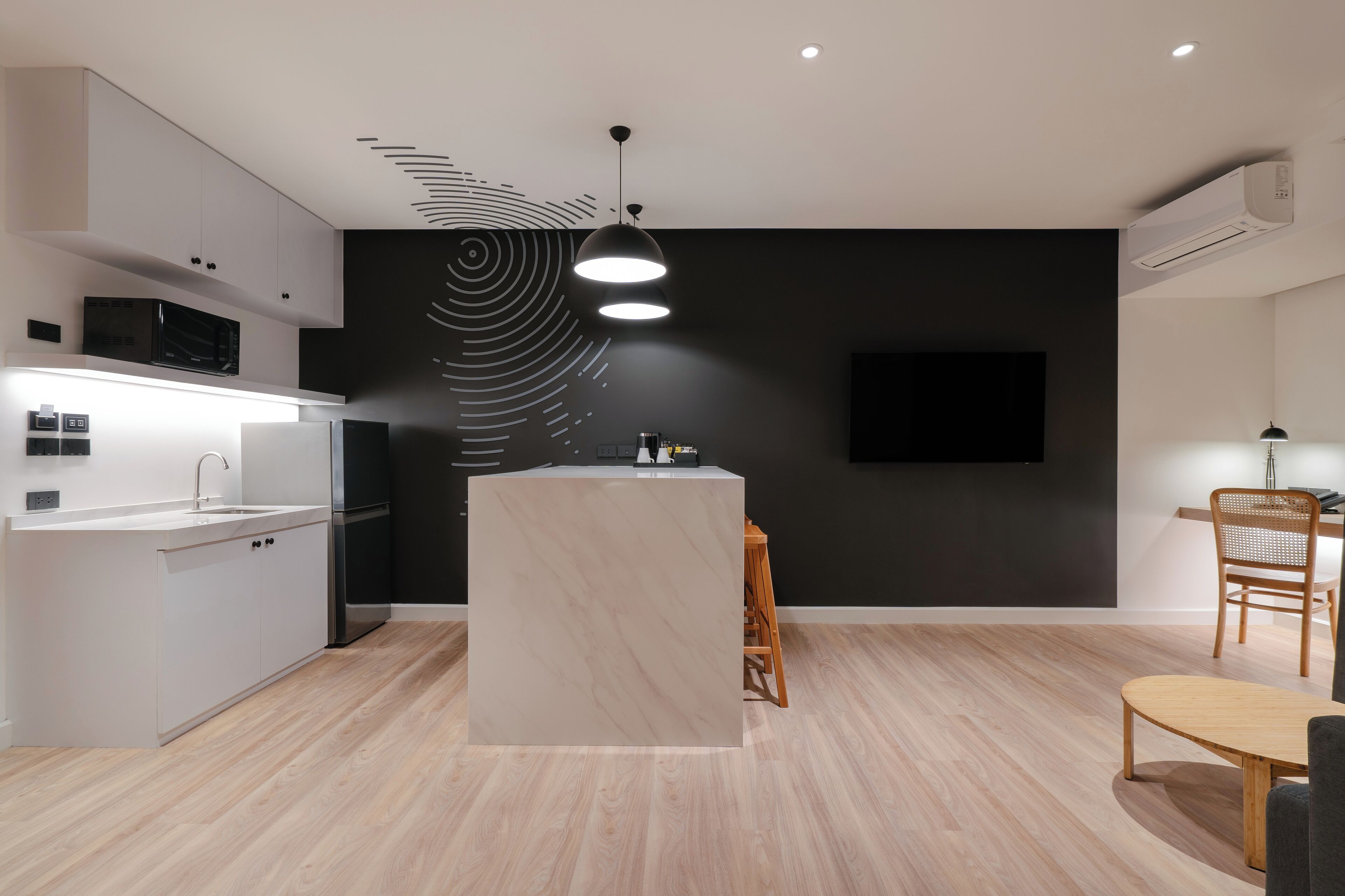 Une cuisine moderne avec des meubles blancs, un îlot central et un mur d’accent noir.