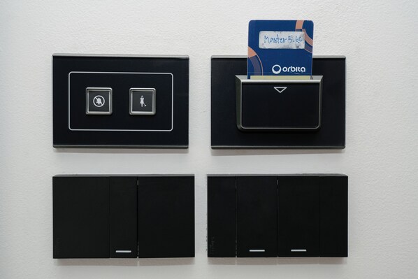 Panel de control montado en la pared con cuatro secciones negras, cada una con iconos diferentes y una ranura para tarjeta en la esquina superior derecha.