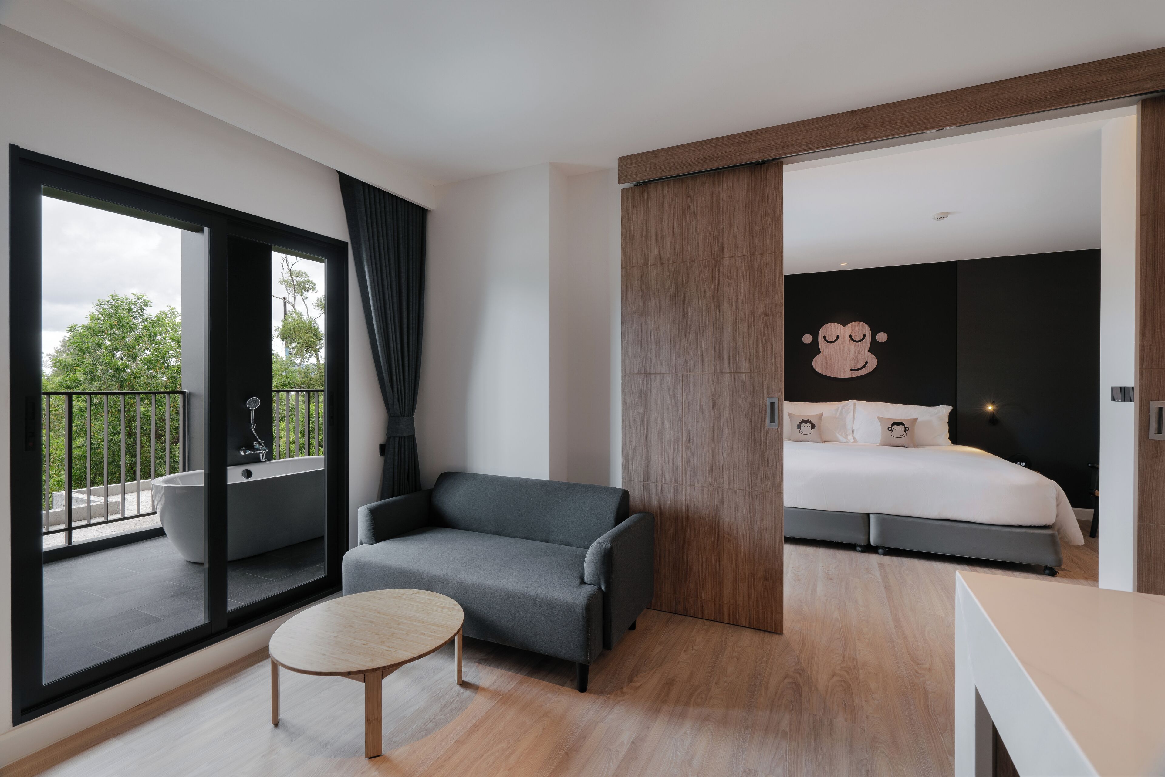 Une chambre d’hôtel moderne dotée d’un balcon, d’un canapé, d’une table ronde et d’un lit agrémenté d’un grand élément décoratif mural.