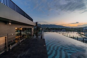 Un edificio moderno con piscina y vistas a un río y montañas.